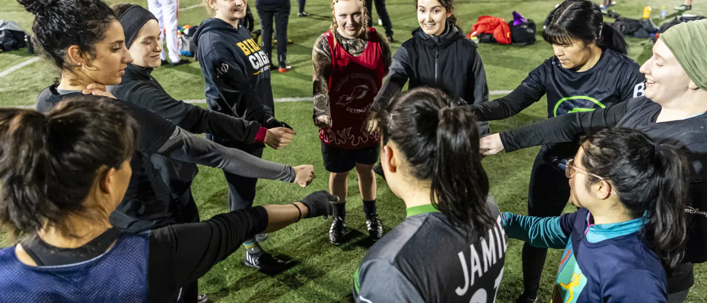 a group of women-matching players with their hands in a circle to cheer