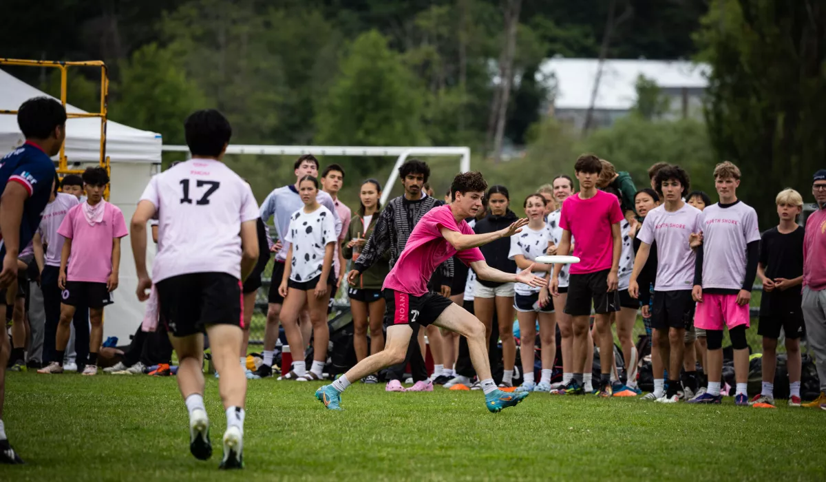 A youth player catching a disc, with a large crowd behind.